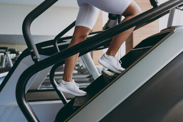 Cropped up photo shot young strong skinny sporty athletic sportswoman woman in white sportswear warm up train run on a treadmill climber stairs machine in gym indoor Workout sport motivation concept.