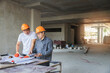 © skarie - Confident team of architect working together in building construction site. They discussing about new startup project. Architect discuss with engineer about project . Architectural concept.