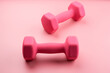 © amixstudio - Two pink female dumbbells isolated on pink background close-up with copy space. Fitness concept, weight loss and sport activity