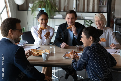 Happy diverse coworkers enjoying pizza party at office meeting table, eating, talking ,laughing, having fun, celebrating corporate success. Office people relaxing during lunch work break