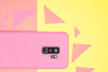 Pink phone on the pink and yellow background with paper triangles