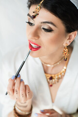 Sticker - Indian bride applying lipstick with cosmetic brush on white