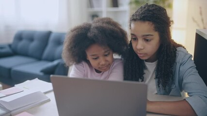 Young sisters with natural black hair watching online lesson, giving high-fives