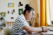 Side view portrait of Asian teenage girl studying at desk at home and writing in notebook, copy space