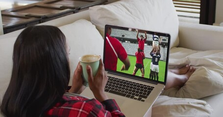 Poster - Composite of woman sitting at home holding coffee watching rugby match on laptop