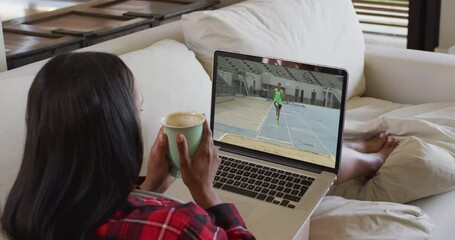 Sticker - Composite of woman sitting at home holding coffee watching athletics long jump event on laptop