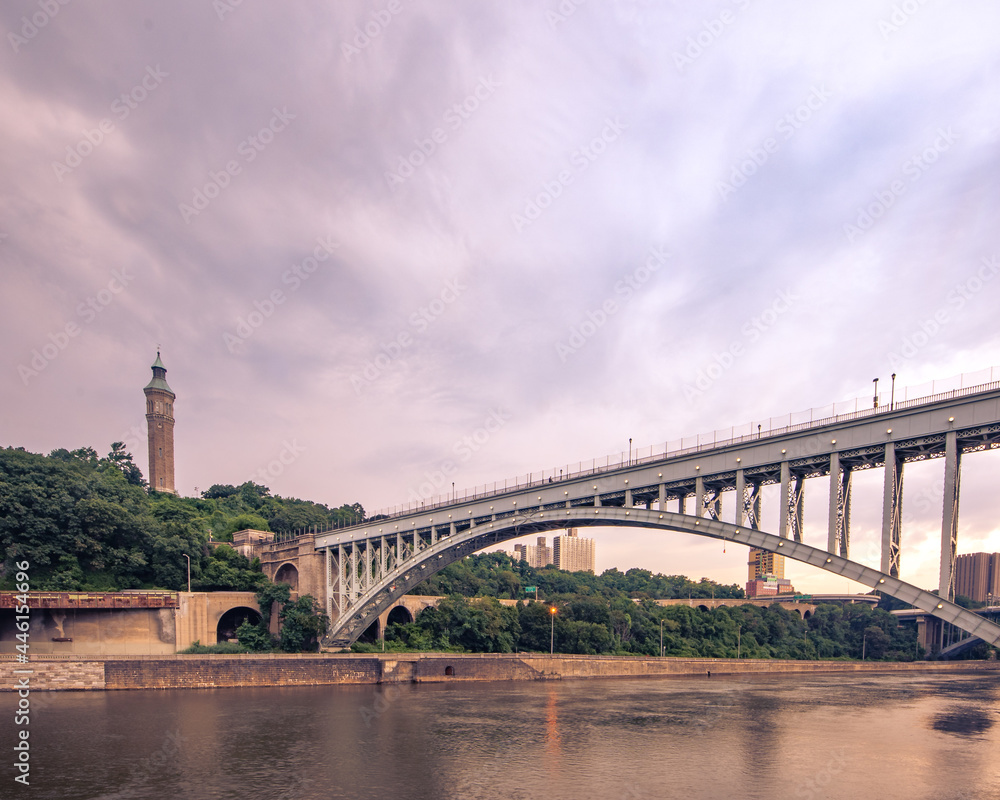 Bronx, NY - USA - July 17, 2021: Wide horizontal view of the historic High Bridge spanning the Harlem River and Highbridge Water Tower is the distance.