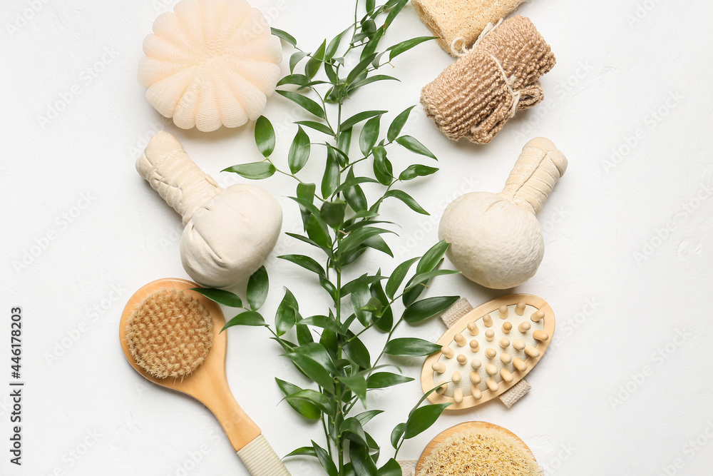 Set of bath supplies and branch on light background