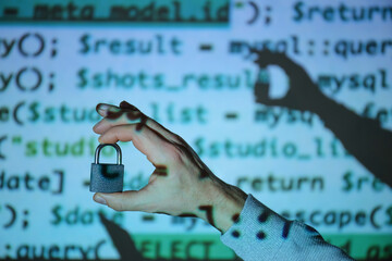 Hand of hacker with padlock near screen of computer