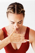 A woman is pressing her right nostril to do alternate breaths or Nadi Shodhana Pranayama.