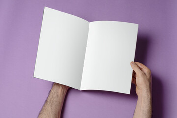 Poster - Hands opening A4 catalog on purple background, mock-up series template ready for your design