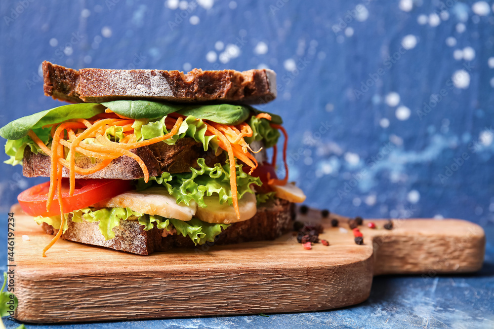 Board with tasty sandwich on color background, closeup