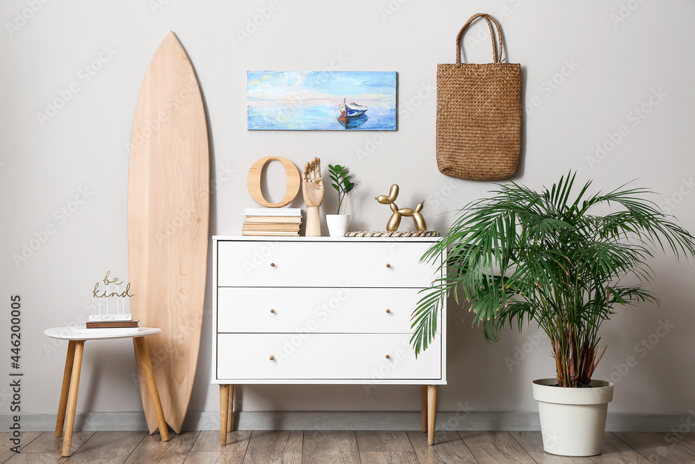Interior of modern stylish room with chest of drawers and surfboard - obrazy, fototapety, plakaty 