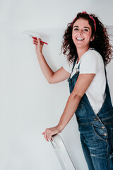 happy caucasian woman painting the room walls with white color. Do it yourself and new home concept