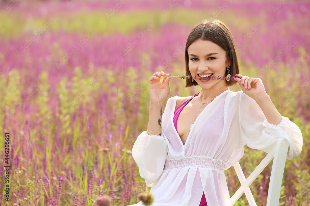 Beautiful young woman relaxing in blooming field