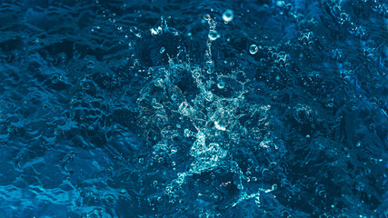 Poster - The water surface is blue with ripples, splashes and bubbles. Abstract natural background. Waves and bursts in sunlight.