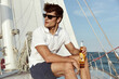 © Drobot Dean - Young man drinking beer on his yacht in sea