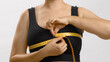 White unrecognizable anonymous lady in black top measures her bust with a tape for bra fitting. Studio no head shot high quality photo image on white background.