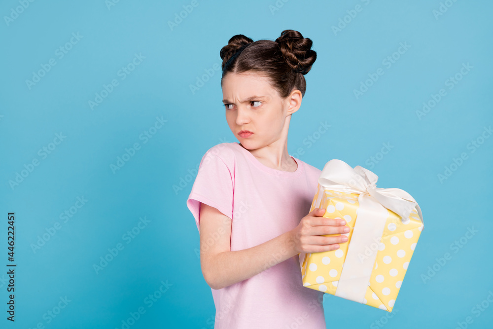 Photo of furious unhappy school girl wear pink t-shirt holding yellow present box looking empty space isolated blue color background - obrazy, fototapety, plakaty 