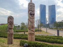 Skyline Of Songdo In South Korea, Wooden Totem Poles Called Jangseung In A Park