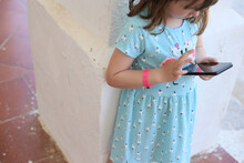 child girl red bracelet uses smartphone screen