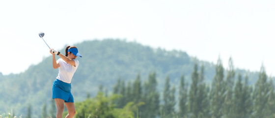 Wall Mural - Golfer sport course golf ball fairway. People lifestyle woman playing game golf and hitting go on green grass and mountain background.  Asia female player game shot in summer