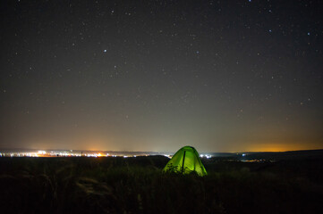 Wall Mural - night landscape tent against the background of the starry sky and city lights