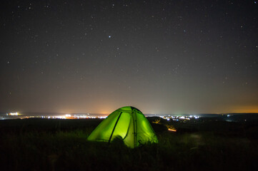 Wall Mural - night landscape tent against the background of the starry sky and city lights