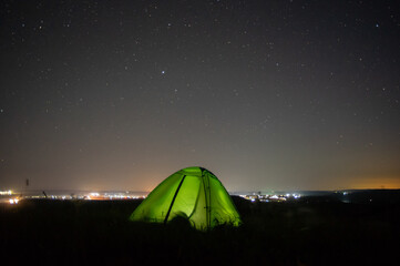 Wall Mural - night landscape tent against the background of the starry sky and city lights