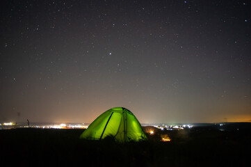 Wall Mural - night landscape tent against the background of the starry sky and city lights
