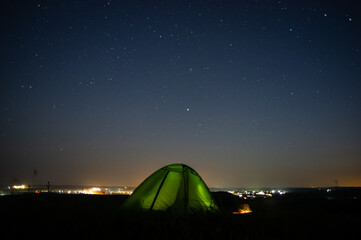 Wall Mural - night landscape tent against the background of the starry sky and city lights