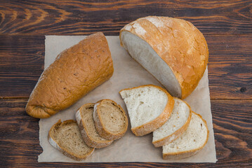 delicious white wheat and rye bread on parchment and a wooden table. the concept of gluten-free and food products, baking