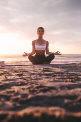 Woman meditating in lotus pose during sunset