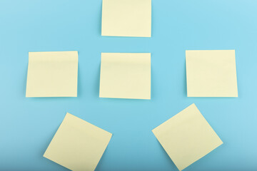 Wall Mural - yellow sticky notes on blue background. Square sticky paper reminders with shadows