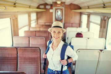 Wall Mural - Enjoying trip. Young pretty woman with rucksack traveling by the train.