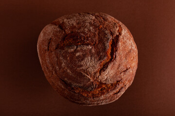 Fresh crusty handcraft bread on brown surface.