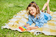 Girl lies on a blanket on grass outdoors and play pop it, kid hands playing with colorful pop It, fidget toy in the backyard of the house on a sunny summer day, summer time vacation.