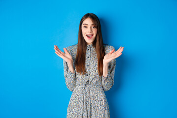 Excited beautiful woman clap hands and congratulate you, praising nice work, applause at camera and smiling, standing on blue background