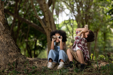 american little girl and boy explorer with his paper binoculars in the nature
