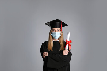 Wall Mural - Student in protective mask with diploma on grey background