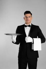 Wall Mural - Handsome butler with tray on light grey background