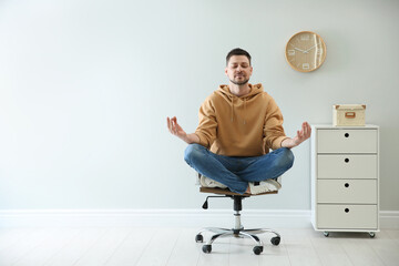 Poster - Calm man meditating in office chair at work. Space for text