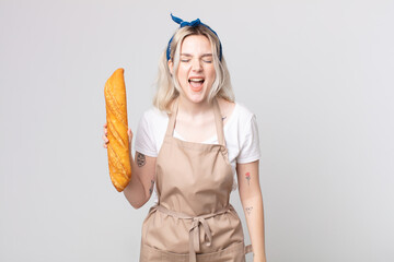 Wall Mural - young pretty albino woman shouting aggressively, looking very angry with a bread baguette