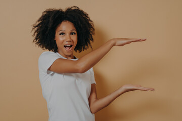 Wall Mural - Exited Afro American beautiful young woman with black curly hair showing with hands example of size