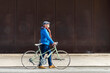 © Cavan Images - Senior man wheeling bicycle on city street holding a handbag