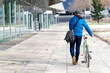 © Cavan Images - Senior man wheeling bicycle on city street holding a handbag