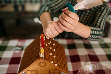 Young Girl Using Icing To Decorate Gingerbread House