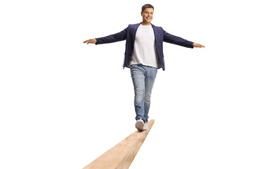 Full length portrait of a young man walking on a wooden beam