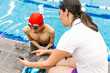 © Marcos - latin swimming woman coach talking some advices to young disabled man in pool in disability concept with hand hypoplasia