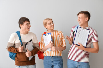 Wall Mural - Students with answer sheets for school test on grey background